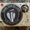 Top‑down view of a Technics SL‑1200 turntable with a Snake Park Records black slipmat featuring a white cobra logo and “Music for the Masses” text.